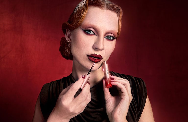 Mujer finalizando su maquillaje de Halloween con un labial rojo